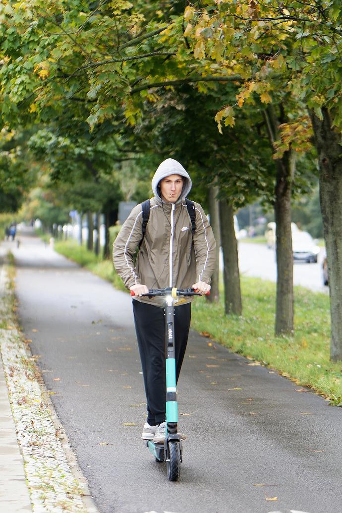 Chico montando patinete eléctrico bajo la lluvia